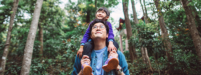 Short Term Medical Member Support, a guy walking through the forest with a child on his shoulders